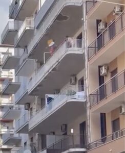 Si affaccia nuda in centro e lancia in strada di tutto