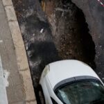 Manto stradale cede per la pioggia, ruota di un'auto nella buca